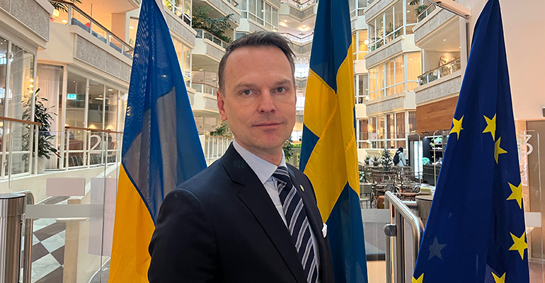 SKRs ordförande Peter Danielsson framför Ukrainas flagga, svenska flaggan och EU-flaggan. .